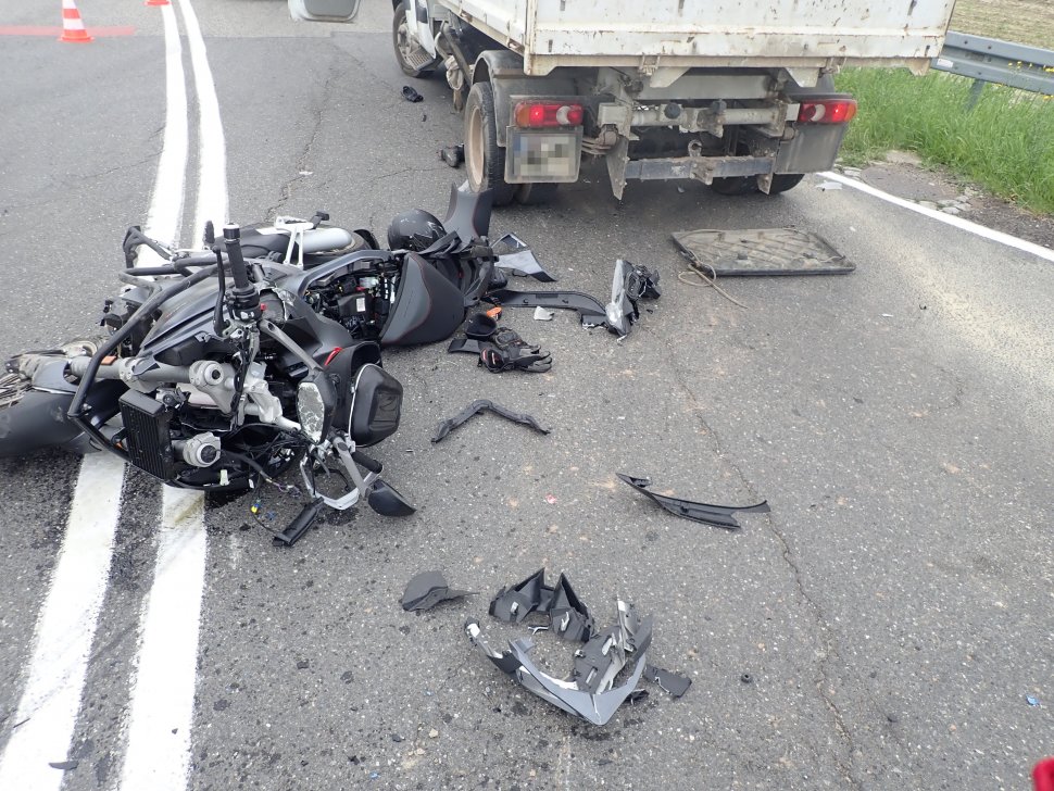fotografia kolorowa: droga, na której leży rozbity motocykl oraz elementy odzieży motocyklisty. Obok wraku motocykla, stoi samochód ciężarowy.