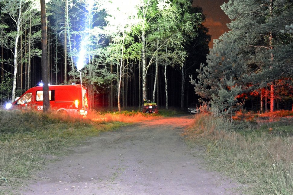 Na zdjęciu widać drogę leśną. Z boku drogi widać wóz strażacki oraz quada, który wbił się w drzewo