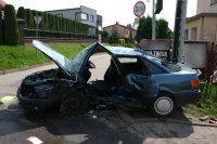 zdjęcie przedstawia rozbity samochód osobowy. Pojazd nie ma drzwi od strony kierowcy, jest złamany, ma otwartą maskę