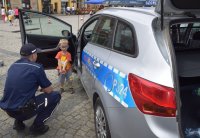 policjant rozmawiający z dzieckiem przy radiowozie