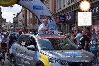 Na fotografii widać samochód osobowy oraz jadącego w nim dyrektora wyścigu Czesława Langa. Za samochodem jedzie peleton kolarzy.