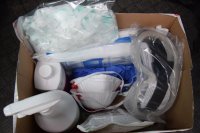 na fotografii widać pudełko, w którym znajdują się środki sanitarne i ochrony osobistej w tym płyny do dezynfekcji, maseczki, lejki, kombinezony