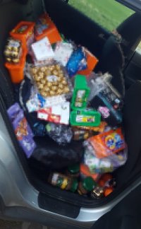 fotografia kolorowa: na tylnej kanapie w samochodzie, luzem leży ogromna ilość produktów spożywczych, chemicznych oraz zabawki