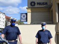 fotografia kolorowa: dwaj policjanci z Wydziału Ruchu Drogowego stoją obok budynku komendy Policji