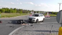 fotografia kolorowa: droga, na której widać przewrócony motocykl i stojący obok niego, samochód osobowy z uszkodzonym przodem