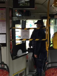 Zdjęcie przedstawia wnętrze autobusu. Przy kabinie kierowcy stoi policjant.