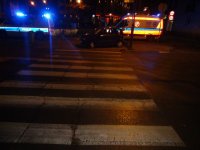 Na zdjęciu widać przejście dla pieszych, na końcu którego widać zaparkowanego na chodniku fiata seicento, policyjny radiowóz oraz karetkę pogotowia