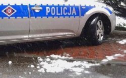 Na fotografii widać bok policyjnego radiowozu. Samochód zaparkowany jest na drodze, na której widać leżący śnieg.