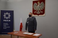 Na zdjęciu widać pełniącego obowiązki Komendanta Powiatowego Policji w Tarnowskich Górach młodszego inspektora Sławomira Bylickiego, Obok którego znajduje się biało-czerwona flaga oraz godło.