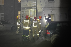 na zdjęciu policjanci i strażacy przy drabinie opartej o budynek w trakcie ewakuacji mieszkańców kamienicy