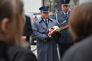 na zdjęciu komendant policji z wiązanką kwiatów w rękach, obok niego przedstawiciel służby więziennej
