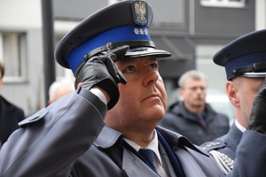 na zdjęciu komendant policji w trakcie oddawania honoru przed tablicą