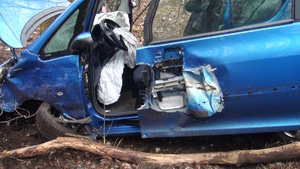 na zdjęciu rozbity niebieski samochód osobowy w rowie przy drzewie